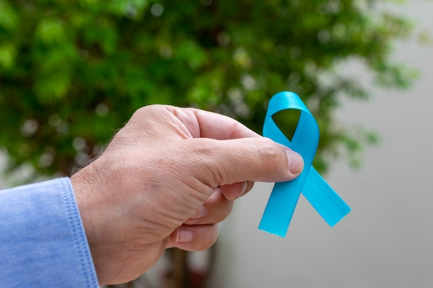 Mão de homem segurando a fita azul. novembro azul. mês de prevenção do câncer de próstata. a saúde dos homens.