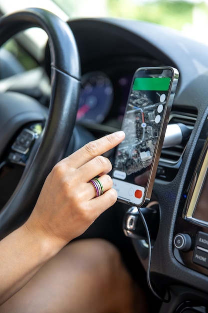 Mão de motorista feminina segurando um telefone com navegador de interface em uma tela