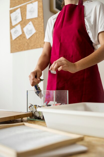 Mão de mulher, colocando pedaços de papel no recipiente de vidro