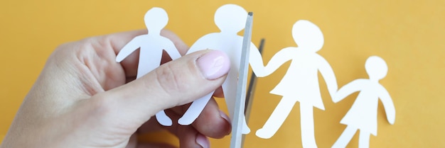 Mão de mulher corta figuras de papel em forma de família com tesoura criança e pais divórcio conceito