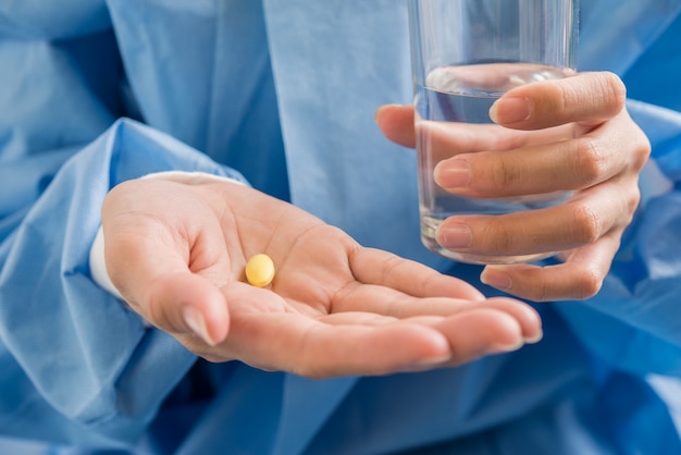 Mão de mulher derrama as pílulas de medicamento fora da garrafa