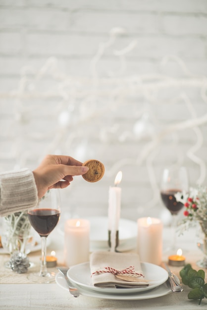 Foto grátis mão de mulher irreconhecível, segurando o biscoito acima da mesa de jantar de natal