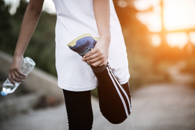 Mão de mulher jovem fitness segurando a garrafa de água após a execução do exercício