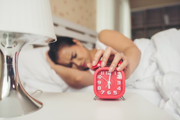 Foto grátis mão de mulher preguiçoso segurando o despertador na cama