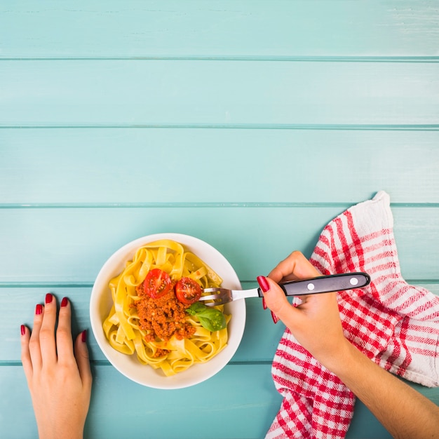 Foto grátis mão de uma mulher comendo macarrão tagliatelle com garfo