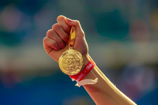 Foto grátis mão de uma mulher levantando uma medalha de ouro olímpica na vitória