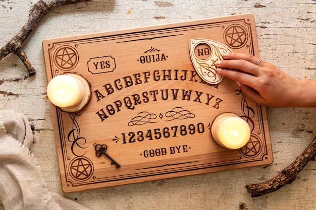 Foto grátis mão de vista superior usando a ferramenta de tabuleiro ouija