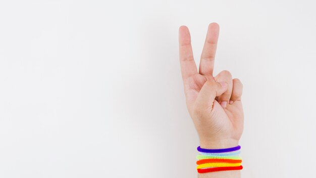 Mão de vitória com pulseira de bandeira do orgulho