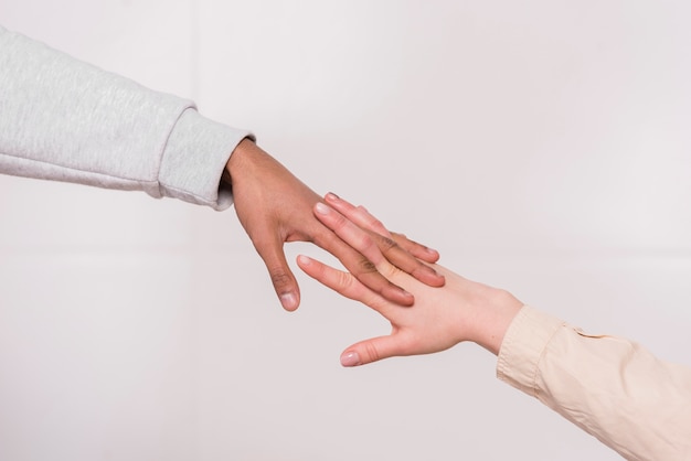 Mão do casal interracial contra fundo branco