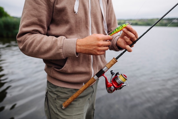 Foto grátis mão do homem segurando isca de pesca e haste