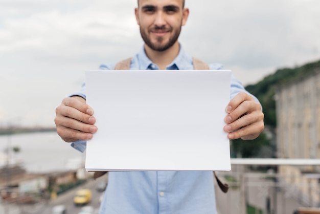 Mão do homem, segurando o papel branco em branco