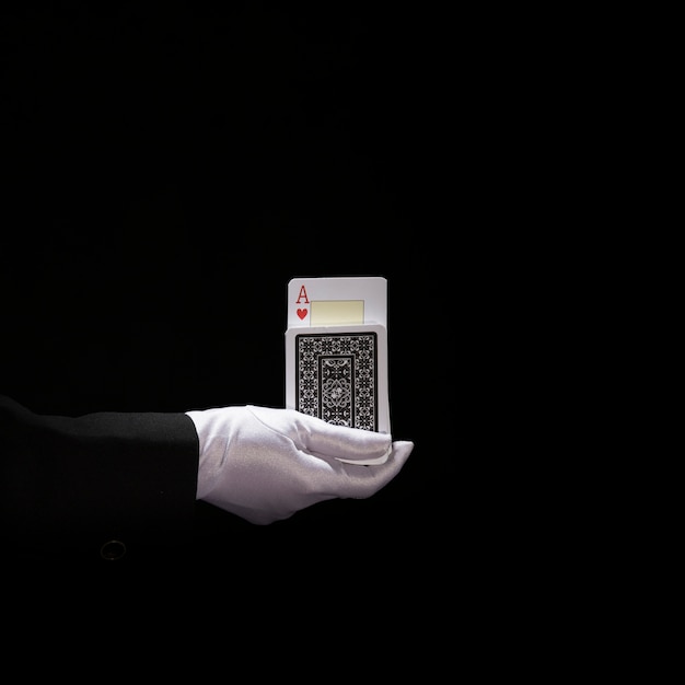 Mão do mago usando luvas brancas, realizando truque em cartas de baralho