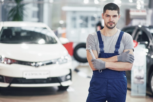 Mão do mecânico de automóveis com chave. Oficina de reparação automóvel