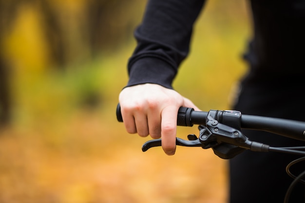 Mão do motociclista no guidão enquanto passeio no parque outono fechar