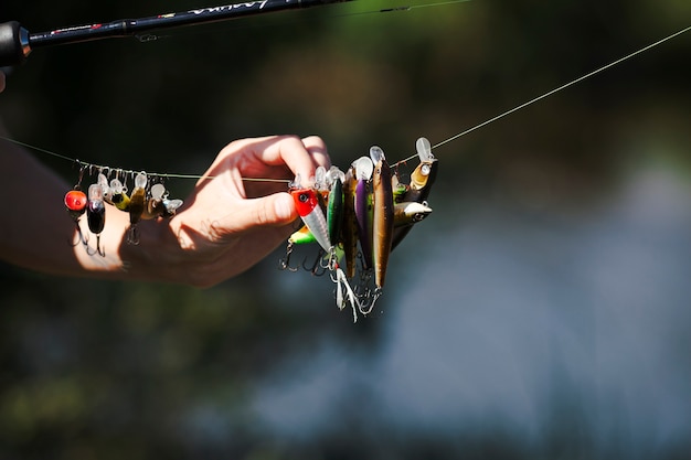 Mão do pescador escolhendo isca na linha de pesca