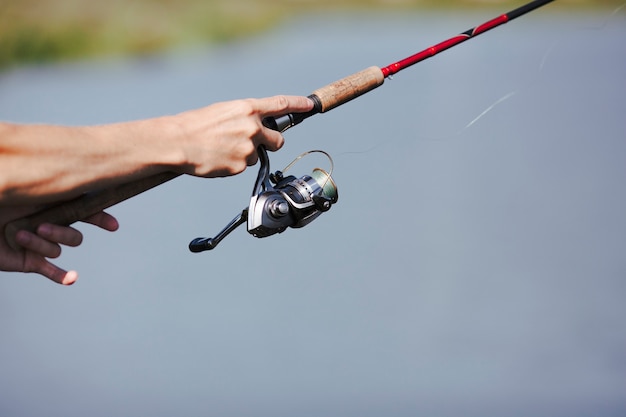 Mão do pescador pesca no fundo desfocado