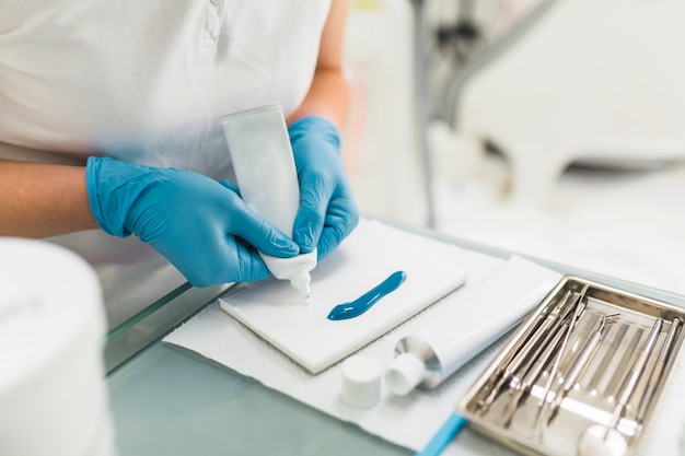 Mão do técnico dental removendo material de impressão de silício do tubo