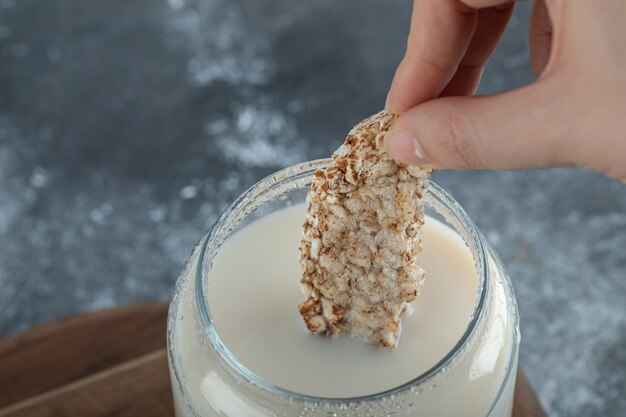 Mão feminina colocando bolo de arroz no leite