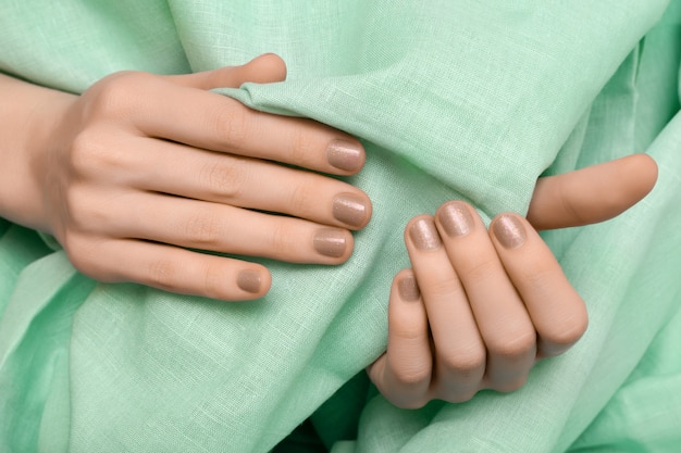 Mão feminina com design de unha glitter bege