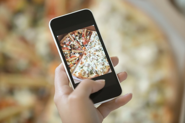 Mão feminina fazendo uma foto de pizza