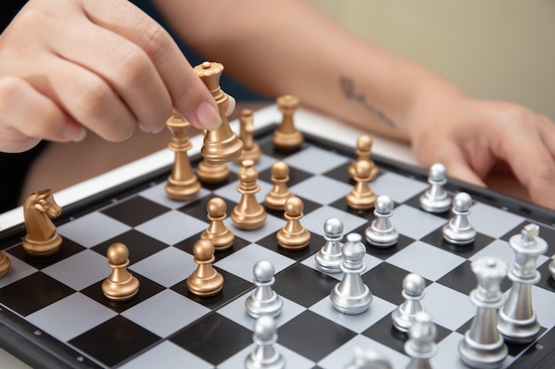 Mão feminina movendo a peça de xadrez no tabuleiro de xadrez