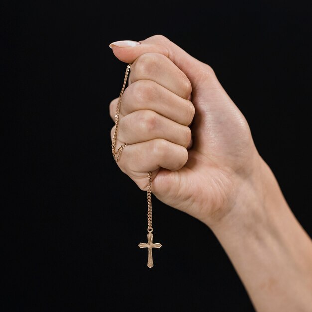 Mão feminina segurando colar de cruz