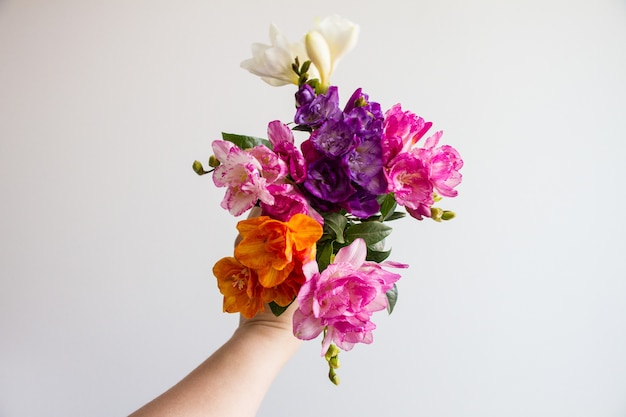 Mão feminina segurando um lindo buquê de flores coloridas