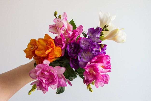 Mão feminina segurando um lindo buquê de flores coloridas