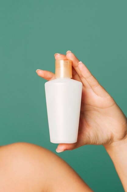 Mão feminina segurando um produto cosmético