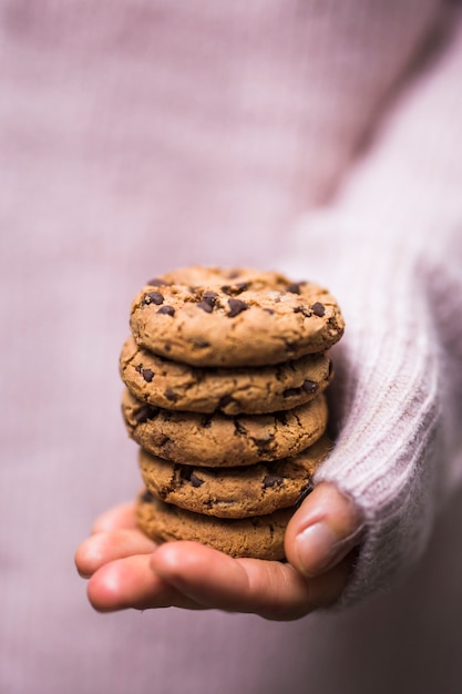Mão humana segurando a pilha de deliciosos biscoitos de chocolate