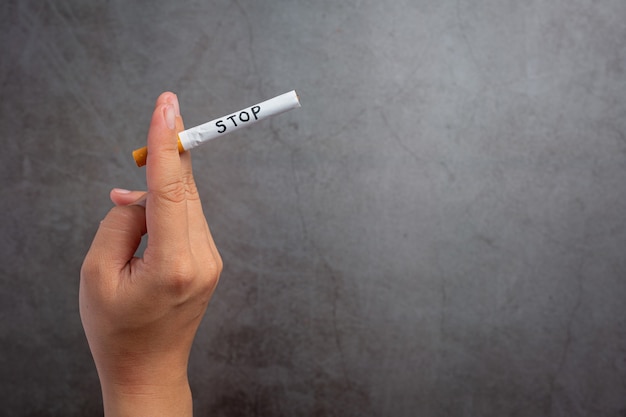 Mão humana segurando o cigarro. Mundo sem conceito do dia do tabaco.