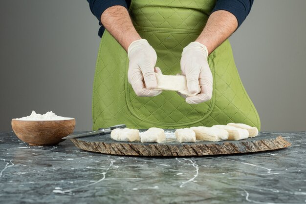 Mão masculina em luvas fazendo massa na mesa de mármore.