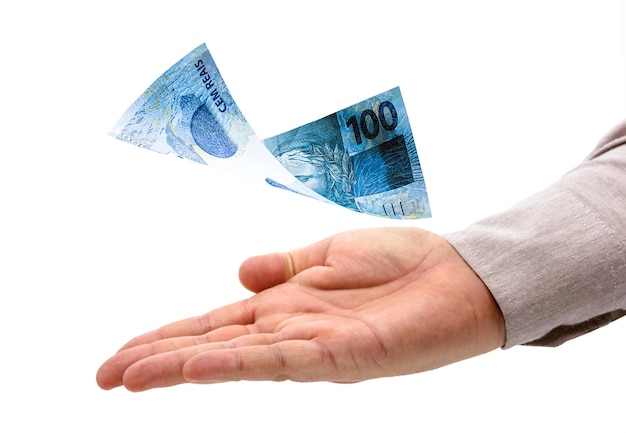Mão masculina recebendo prêmio, nota de 100 reais caindo em sua mão, grande prêmio ou pagamento