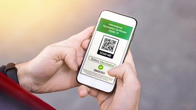 Mão masculina segurando um smartphone com código QR COVID-19 do Certificado Internacional de Vacinação