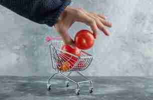 Foto grátis mão masculina tirando tomate do carrinho de compras