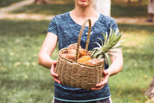 Mão mulher, segurando, cesta, cheio, de, frutas frescas