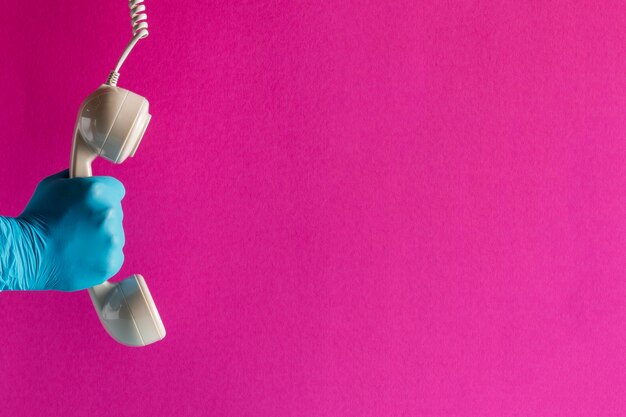 Mão na luva segurando o receptor do telefone com espaço de cópia