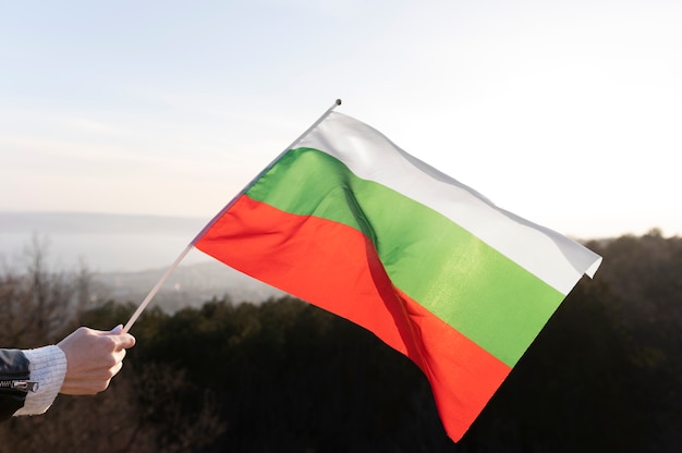 Mão segurando a bandeira da Bulgária ao ar livre