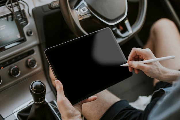 Mão segurando a caneta stylus na tela do tablet em um carro