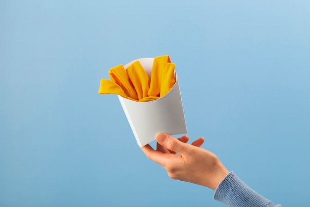 Mão segurando batatas fritas feitas de roupas