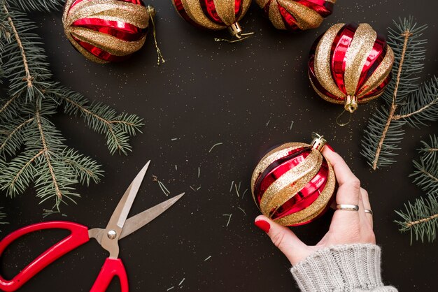 Foto grátis mão segurando bauble natal perto de galhos de abeto