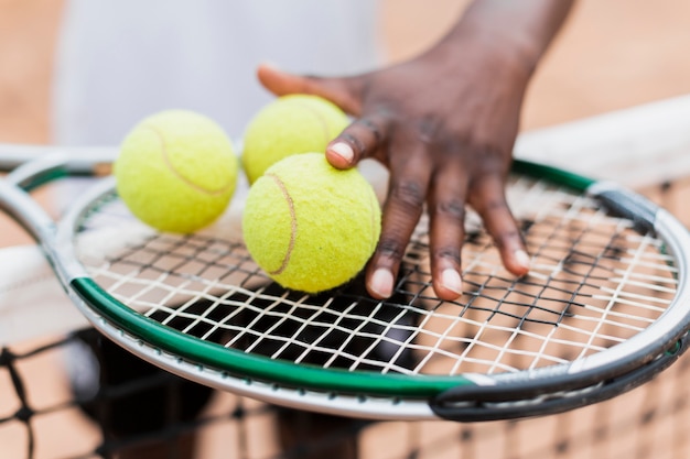 Mão segurando bolas e raquete de tênis