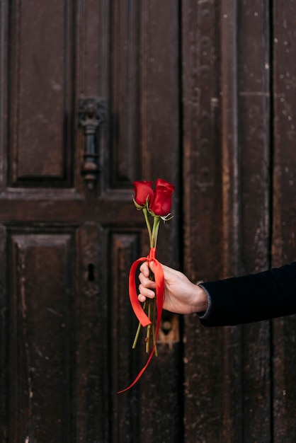 Mão segurando buquê de rosas vermelhas