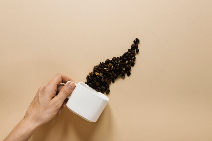 Foto grátis mão segurando copo branco com grãos de café