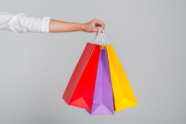 Mão segurando muitas sacolas coloridas