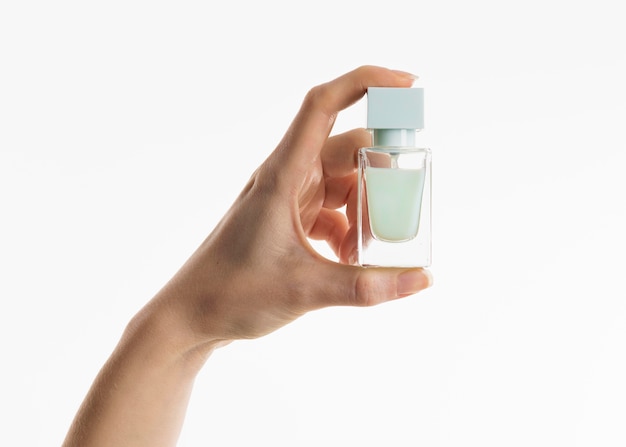 Mão segurando o frasco de perfume