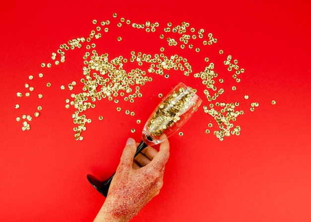 Foto grátis mão segurando o vidro com glitter dourado