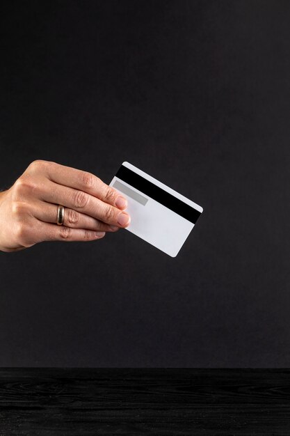 Mão segurando um cartão de crédito em fundo preto