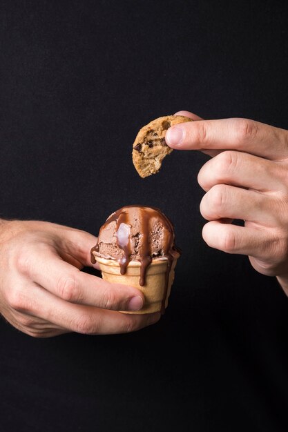 Mão segurando um delicioso sorvete com biscoito