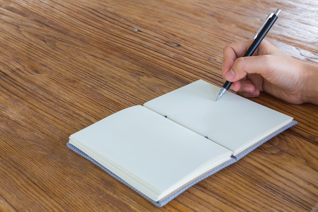 Foto grátis mão segurando uma caneta ao lado de um caderno em branco